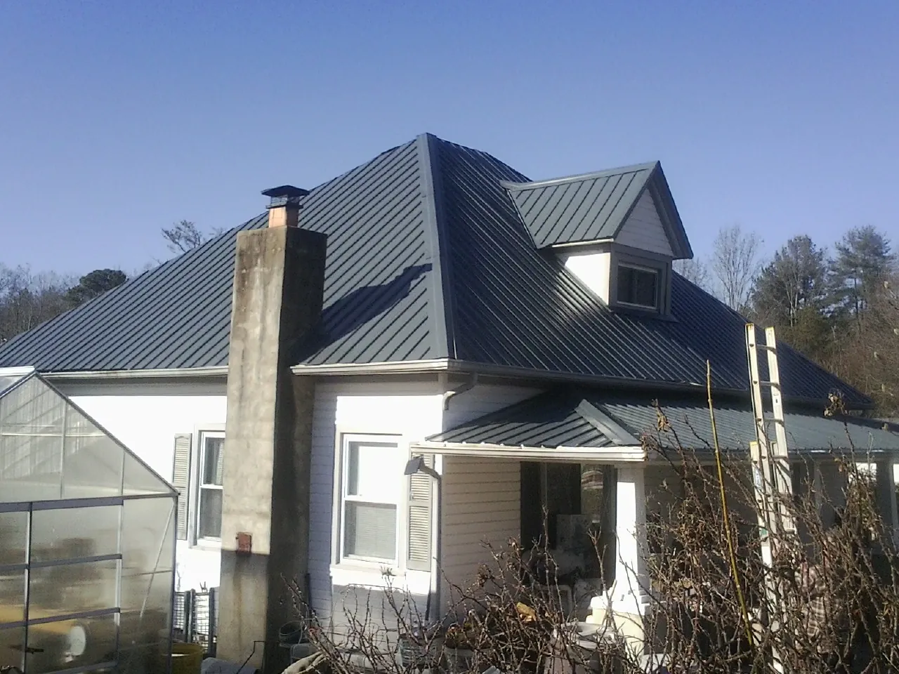 Dark blue standing seam metal roof on a white farmhouse with dormer — Slate & Tile Roof Repair by Roofing Brothers in Sequim