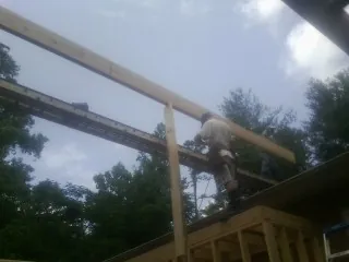Carpenter setting a ridge beam over a new addition frame — Ice Dam Removal by Roofing Brothers in Sequim