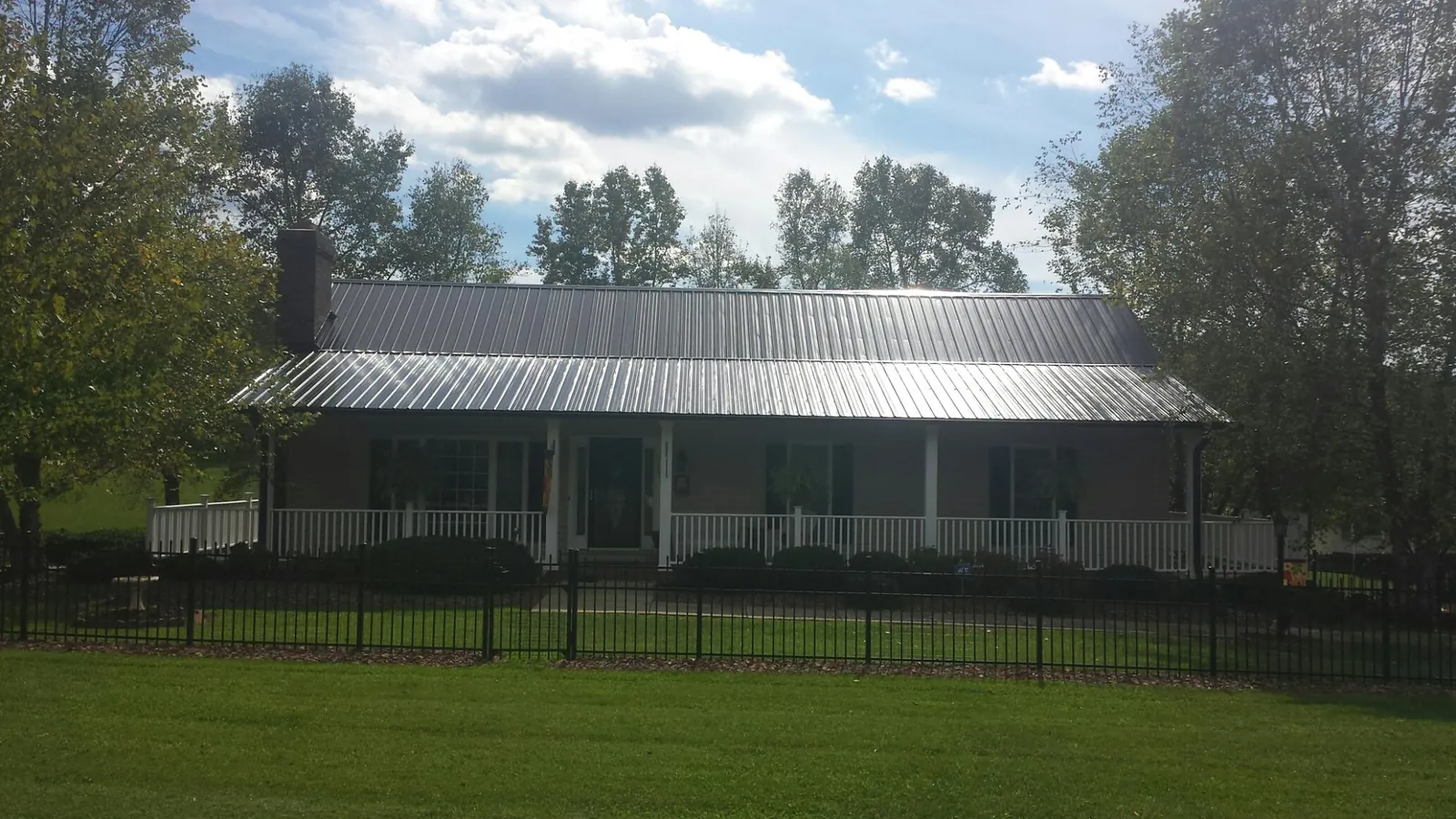 Gray metal roof on a brick ranch with a full width front porch — Gutter Guard Installation work by our crew in Sequim