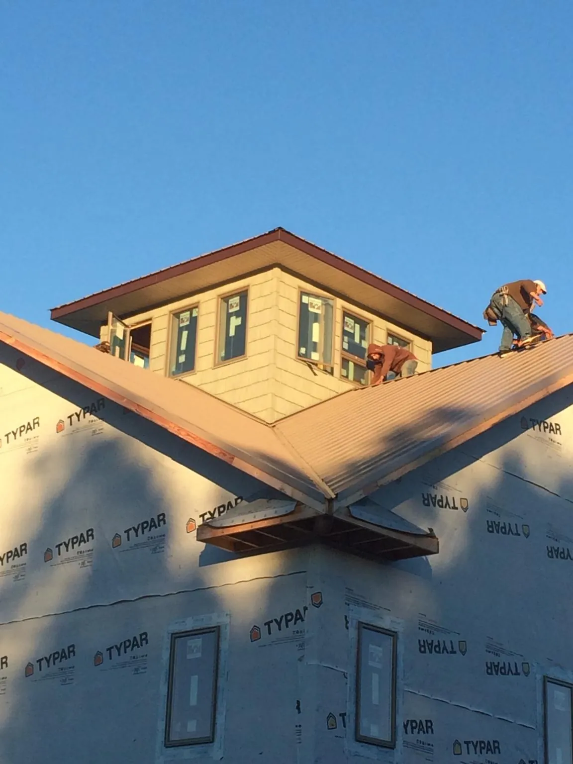 Roofers working around a rooftop cupola on a new metal roof at sunset — Roof Waterproofing in Sequim by Roofing Brothers